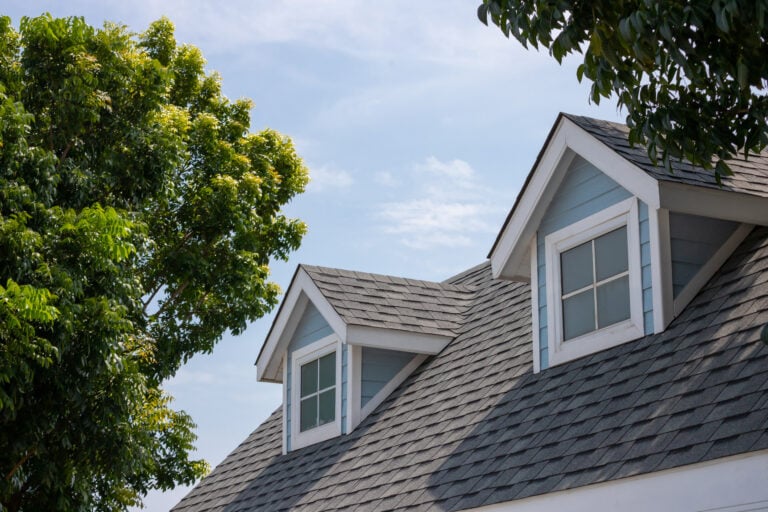 Roof shingles with garret house on top of the house among a lot of trees.