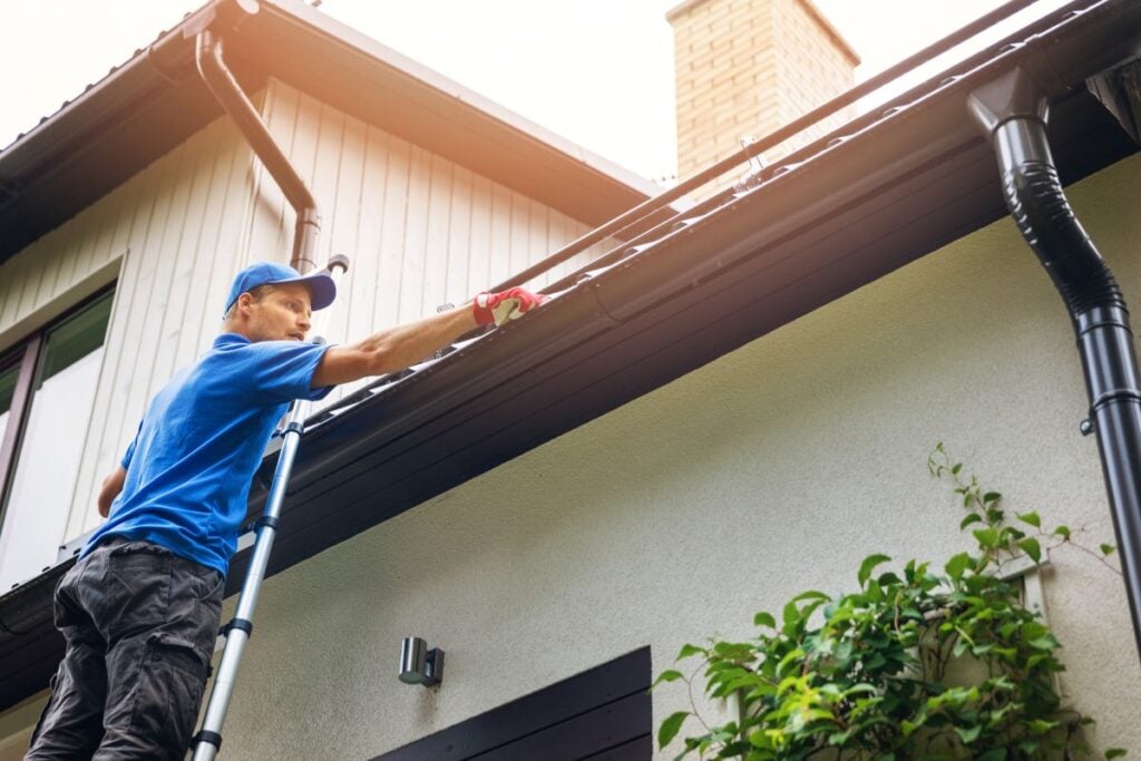 seamless gutters worker using blue uniform doing maintenance to water system