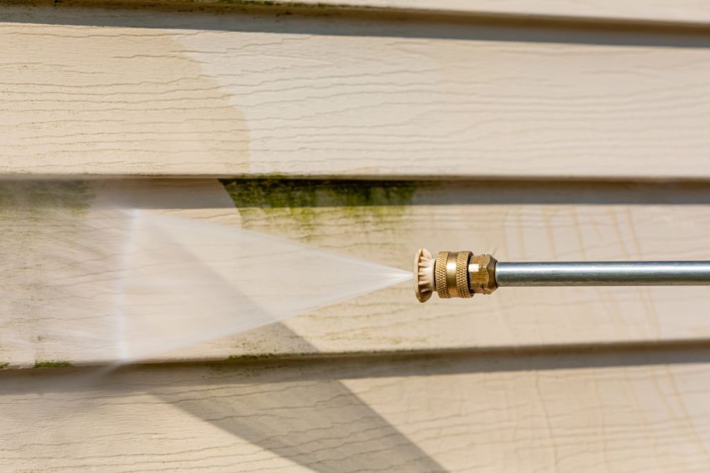 Cleaning algae, mold and mildew from vinyl siding of house with pressure washer